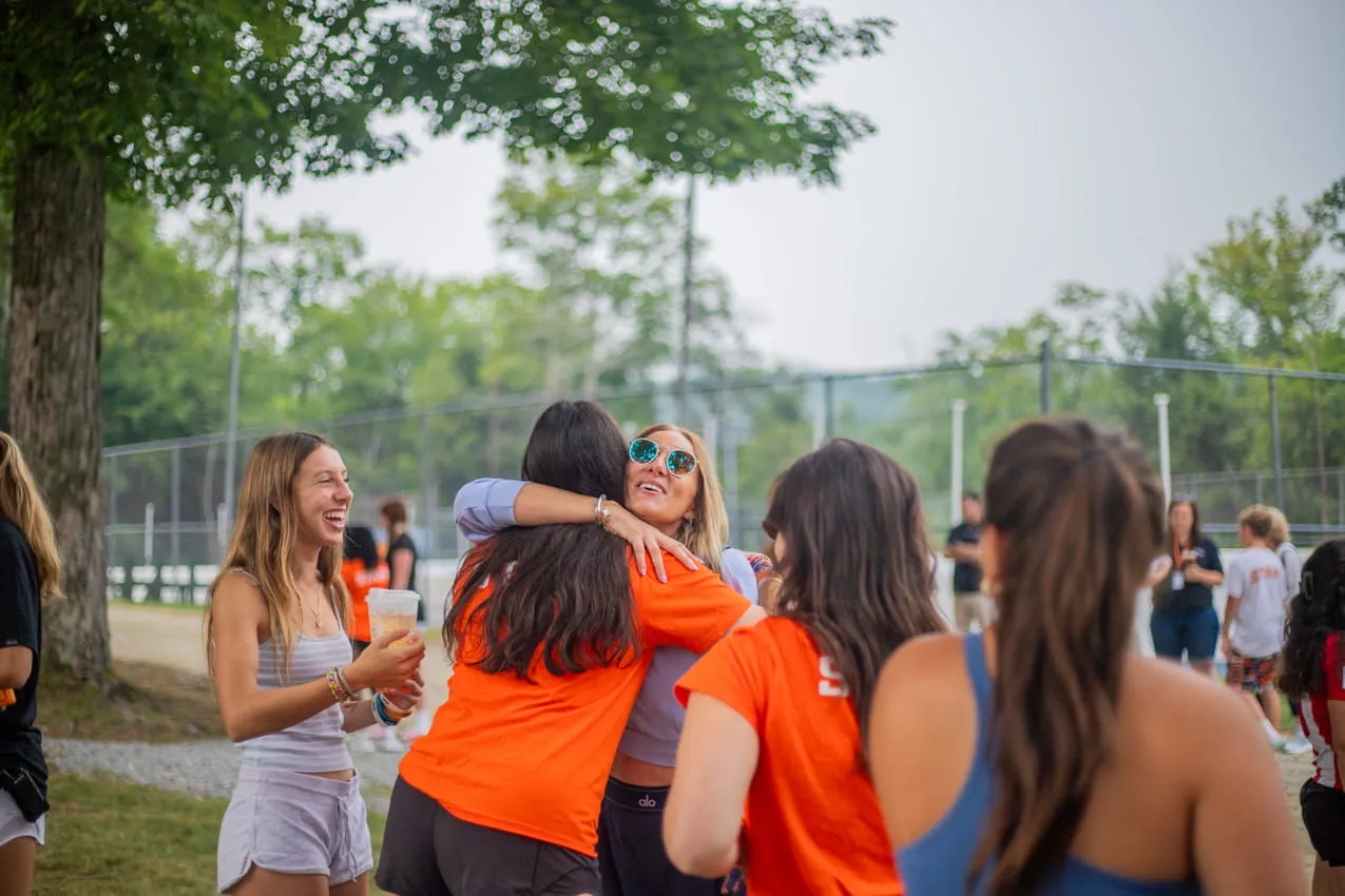 Camp Lenox staff members hugging outdoors at camp