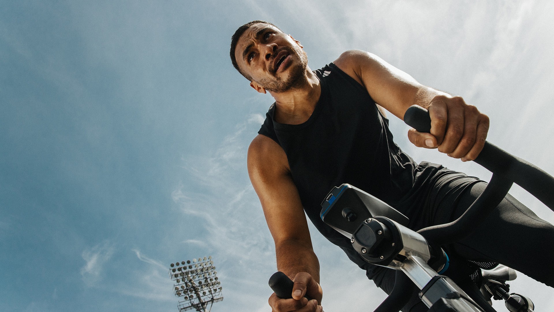 Mann trainiert auf einem Indoor-Fahrrad unter freiem Himmel – effektives Cardio-Training zur Steigerung der Ausdauer.