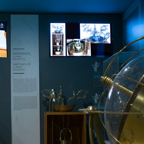 博物館展品,展示牆上資訊展板、一個大型黃銅及玻璃地球儀,以及陳列架上的各種科學儀器。