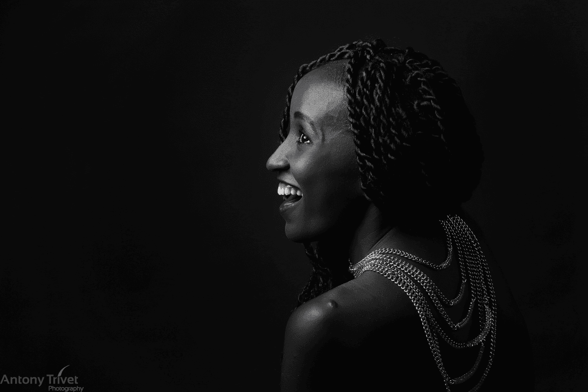Smiling woman sitting at desk with a computer, surrounded by plants.