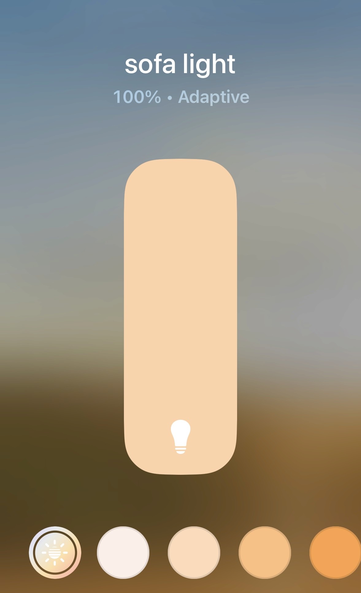 A smartphone screen displays a light control app for a "sofa light," showing a slider set to 100% brightness with adaptive lighting, alongside a range of color temperature options at the bottom.