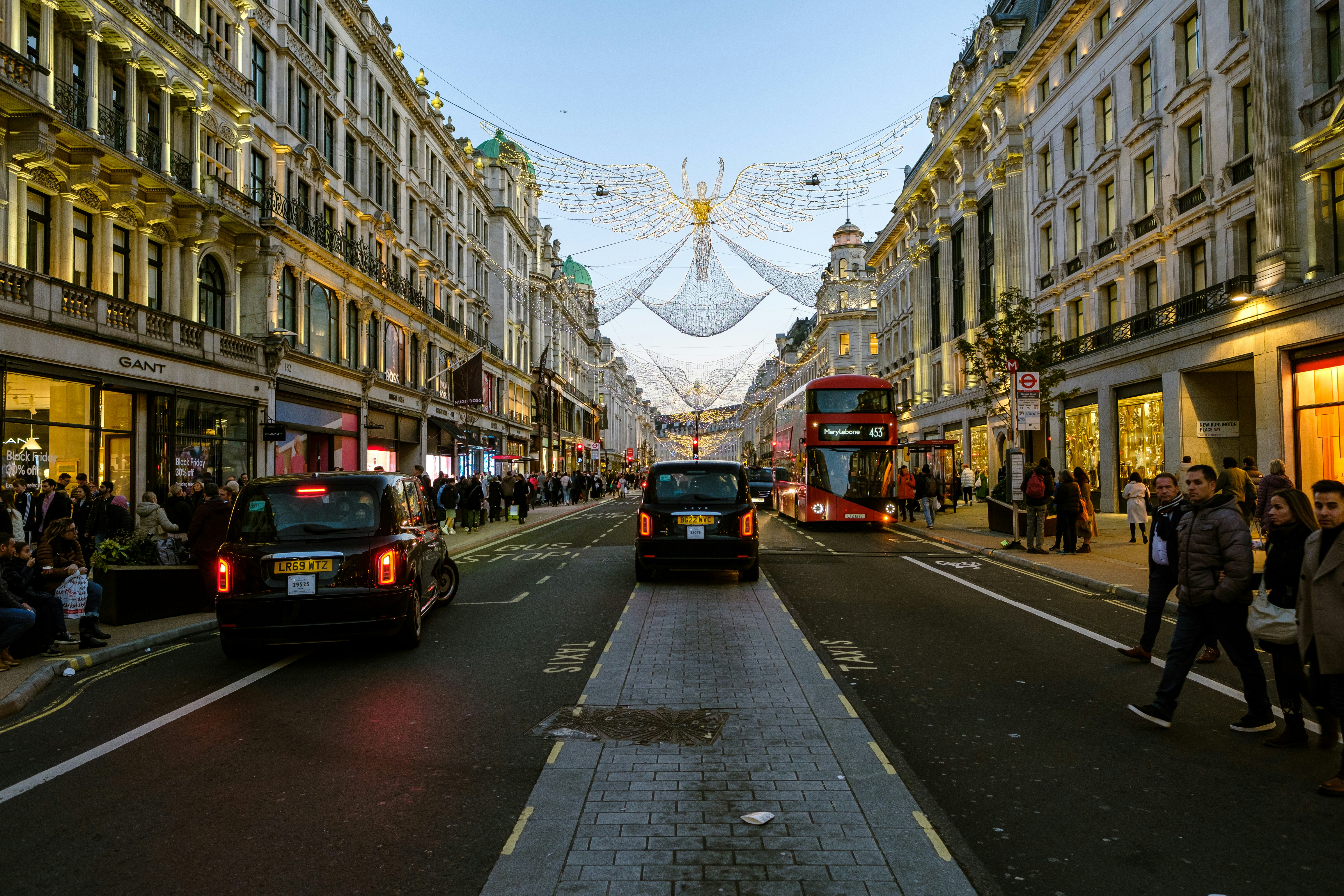 London High Street with christmas lights in the shape of an angel overhead. Cars and busses either side.