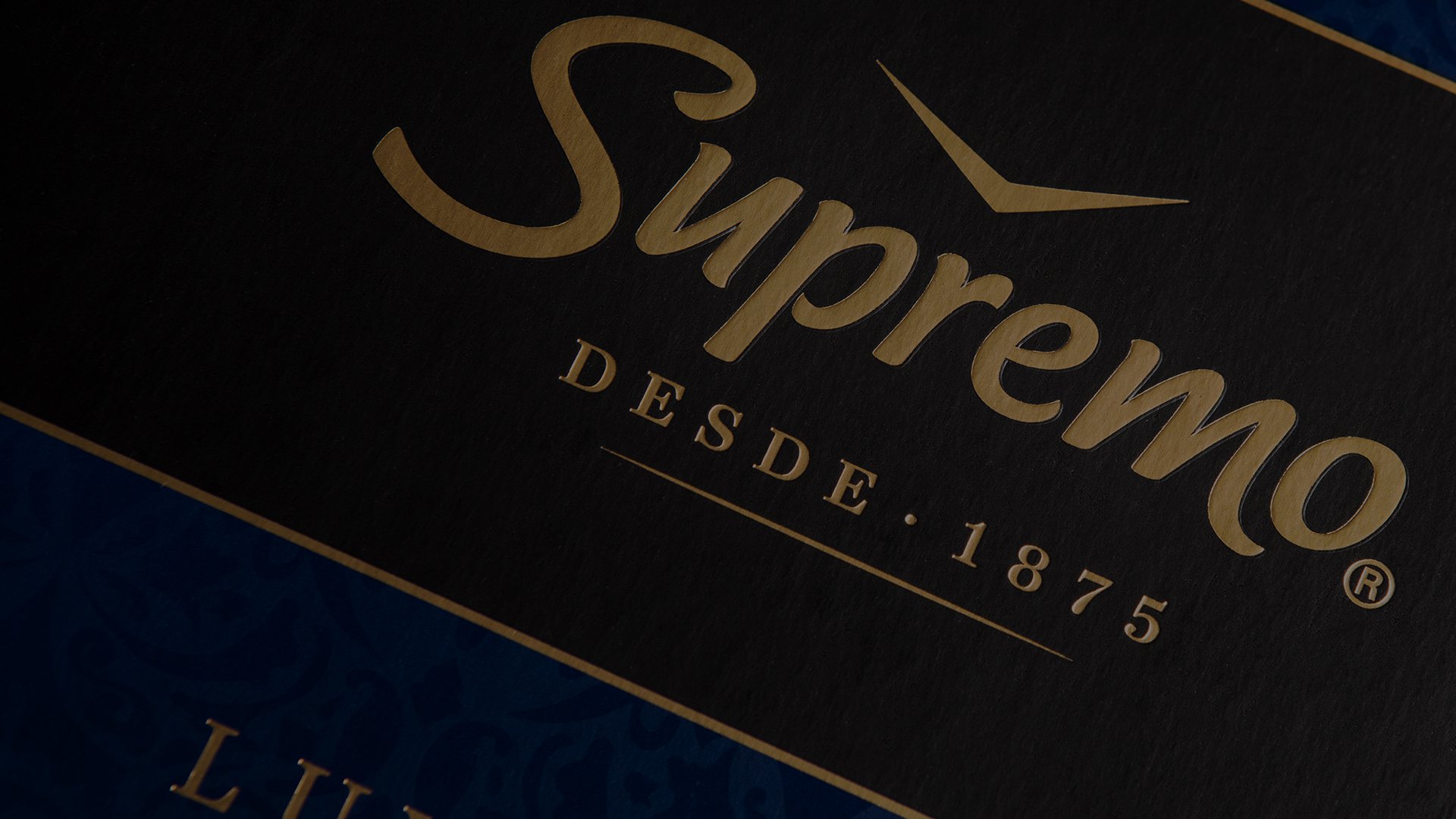 Dark, elegant design featuring the word "Supremo" in gold script with "Desde 1875" below, conveying luxury and heritage on a textured background.