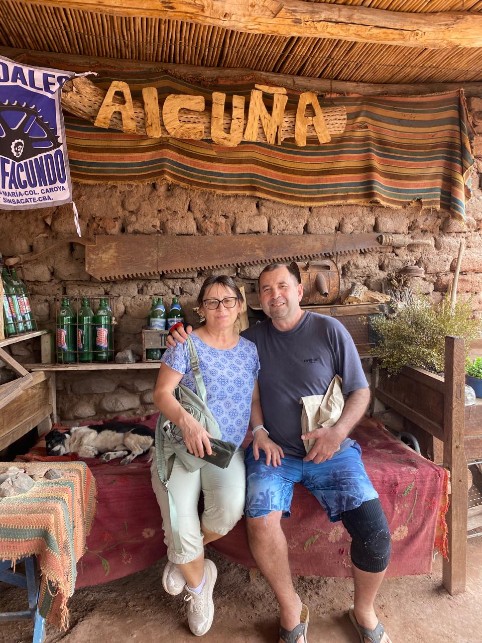 Mujer sentada sobre un tronco frente a una cascada doble en un bosque frondoso de Argentina.