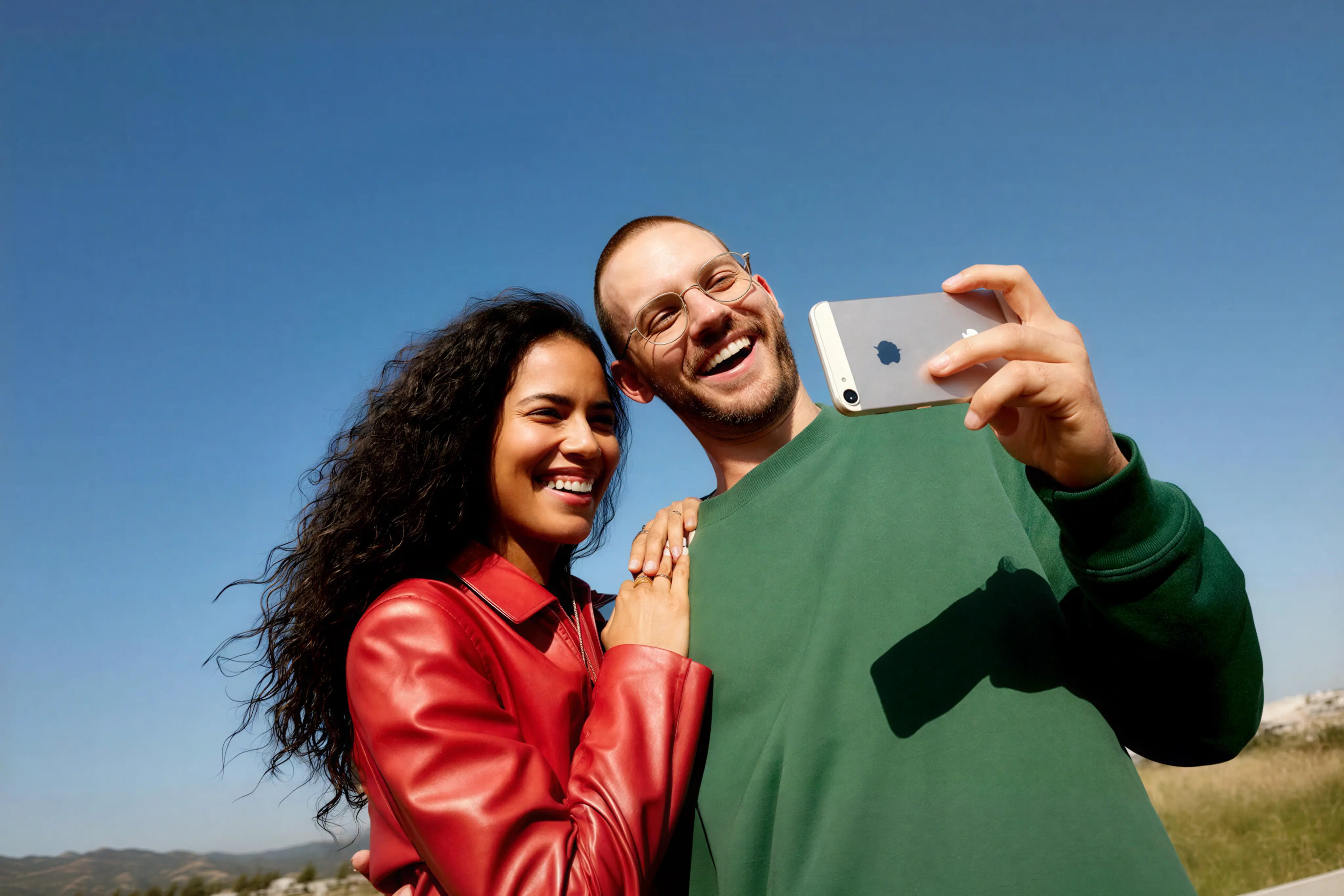 Two friends taking a selfie together against a clear blue sky
