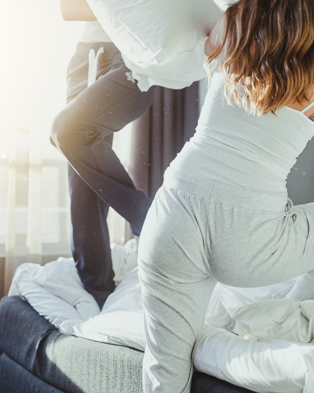 Woman wearing light grey sweatpants and cropped top, slim fit, lounge outfit.