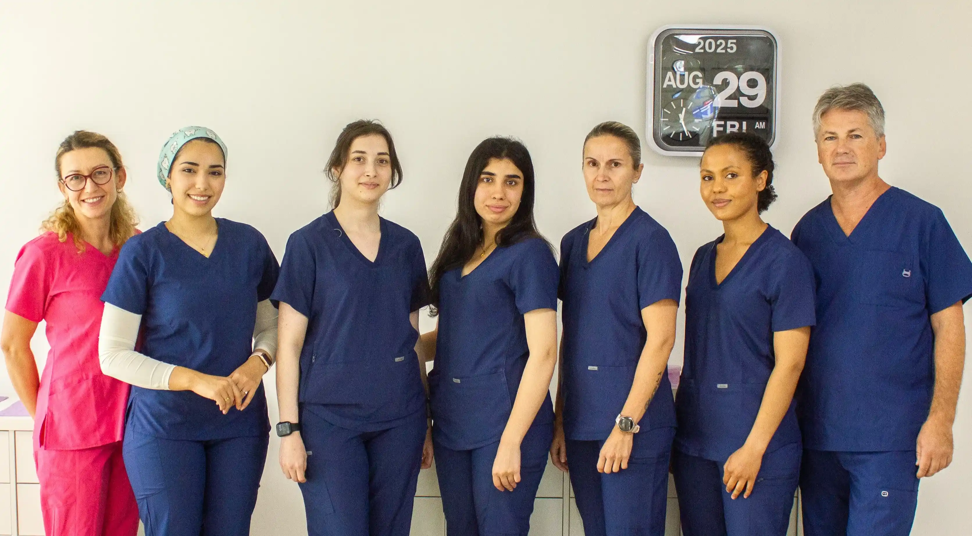 Tannlegeteamet ved Haugenstua Tannlegesenter samlet i klinikken, iført arbeidsantrekk og klare til å ta imot pasienter med et smil.