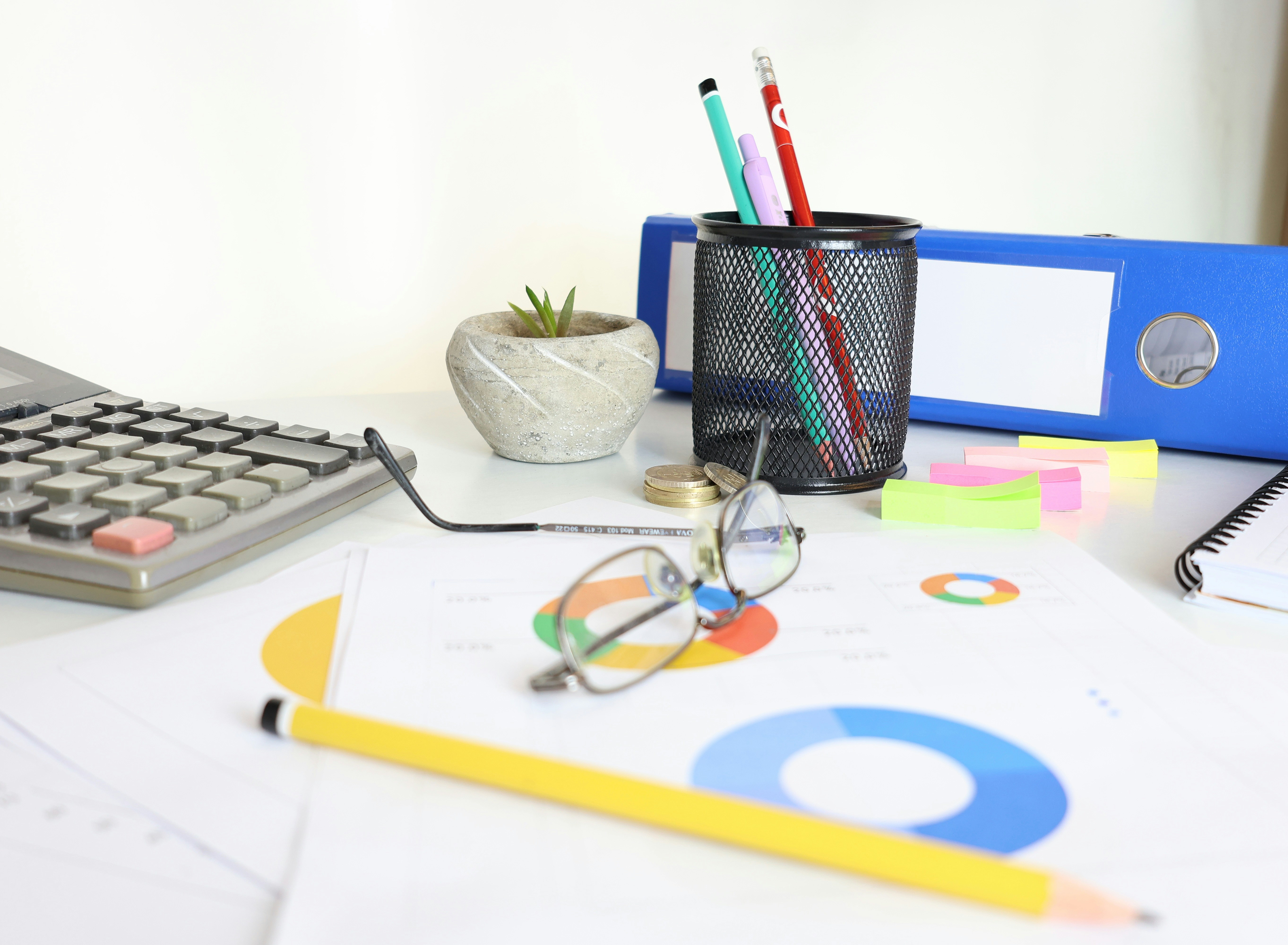 Desk with calculator, glasses, charts, and office supplies