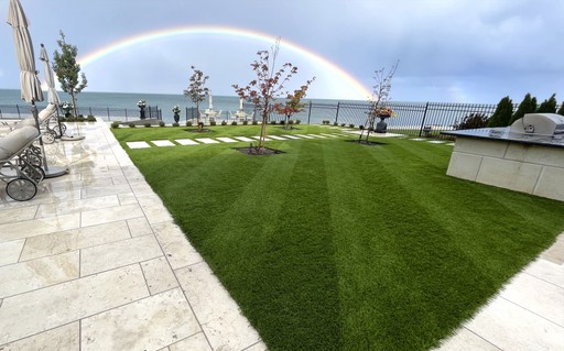 A vibrant rainbow arches over a cozy backyard provided by AGL Grass, adding color to the serene outdoor space.