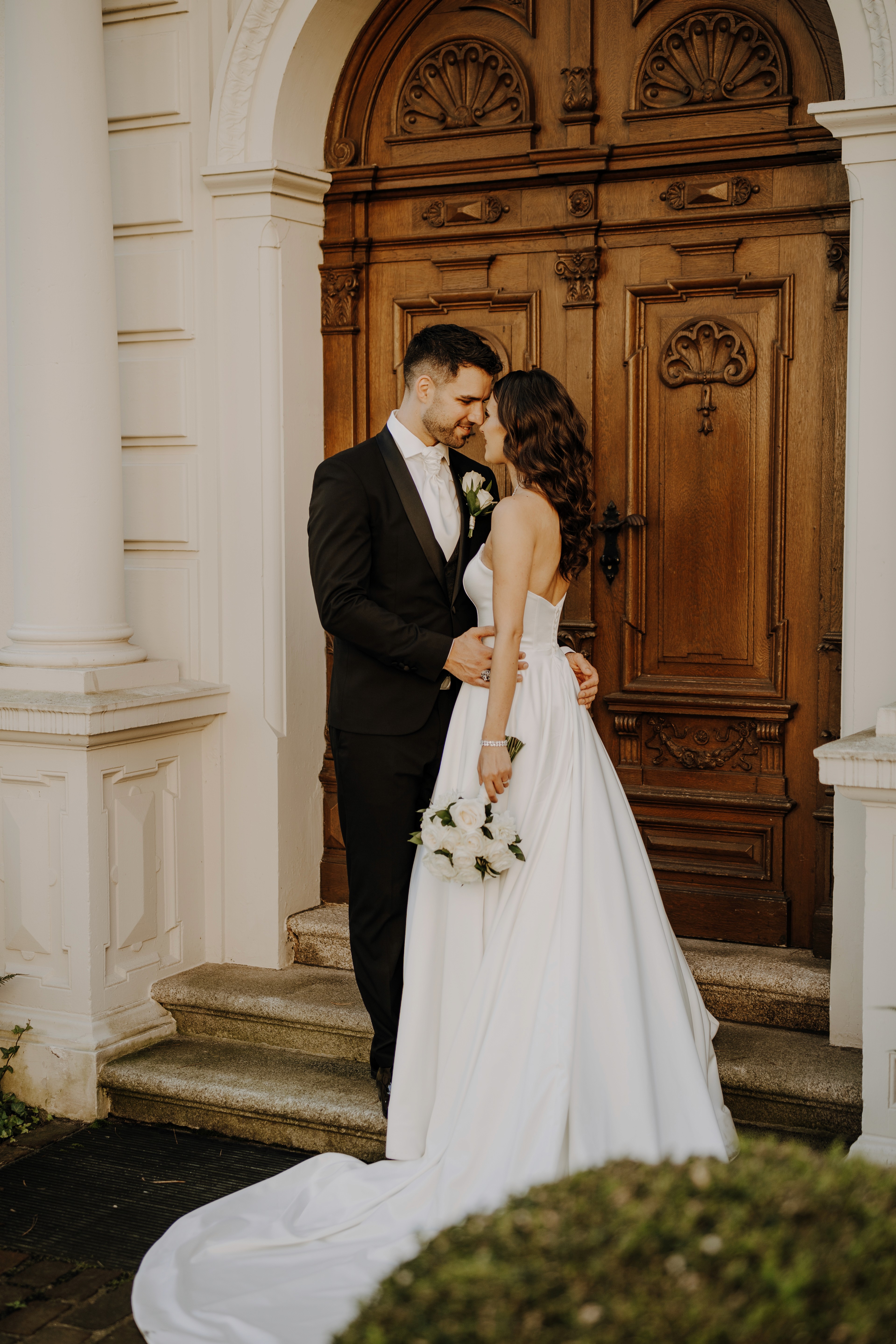 13. Brautpaar vor verzierten Holztüren – elegante Hochzeitsportraits an historischer Location