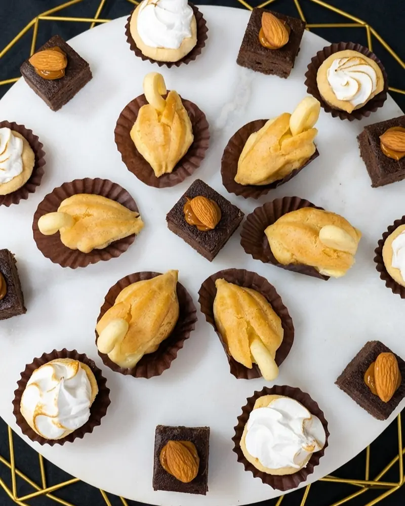 Surtido de pastelería fina con mini brownies y profiteroles para coffee breaks de empresas en Santiago.