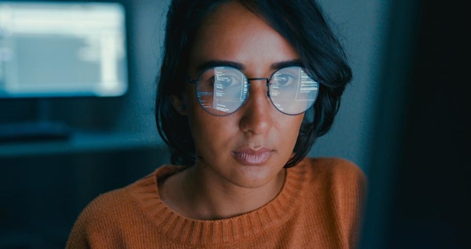 A man with glasses and a brown shirt, crossing his arms.