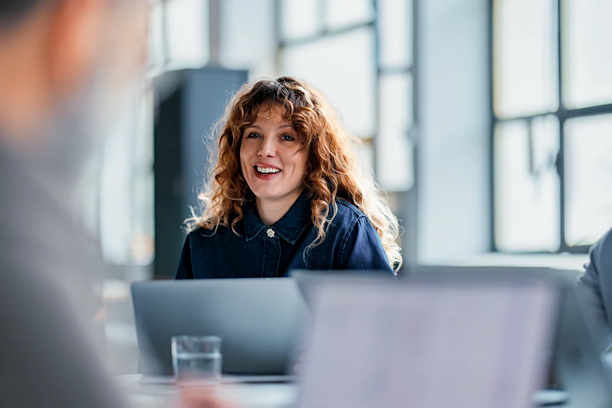 Legal professional smiling during a meeting at a desk, representing collaborative decision-making and modern legal practice.