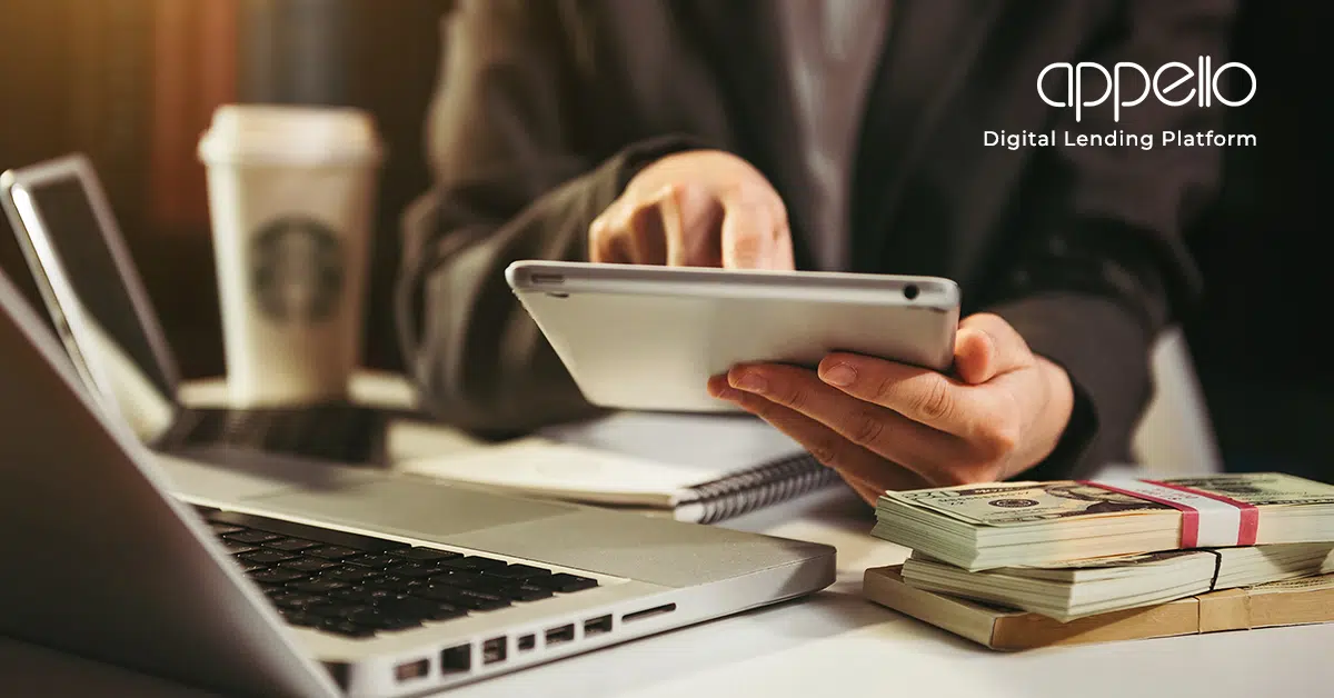 A business professional using a tablet, surrounded by a laptop, cash stacks, and a coffee cup, representing digital lending and financial technology solutions.