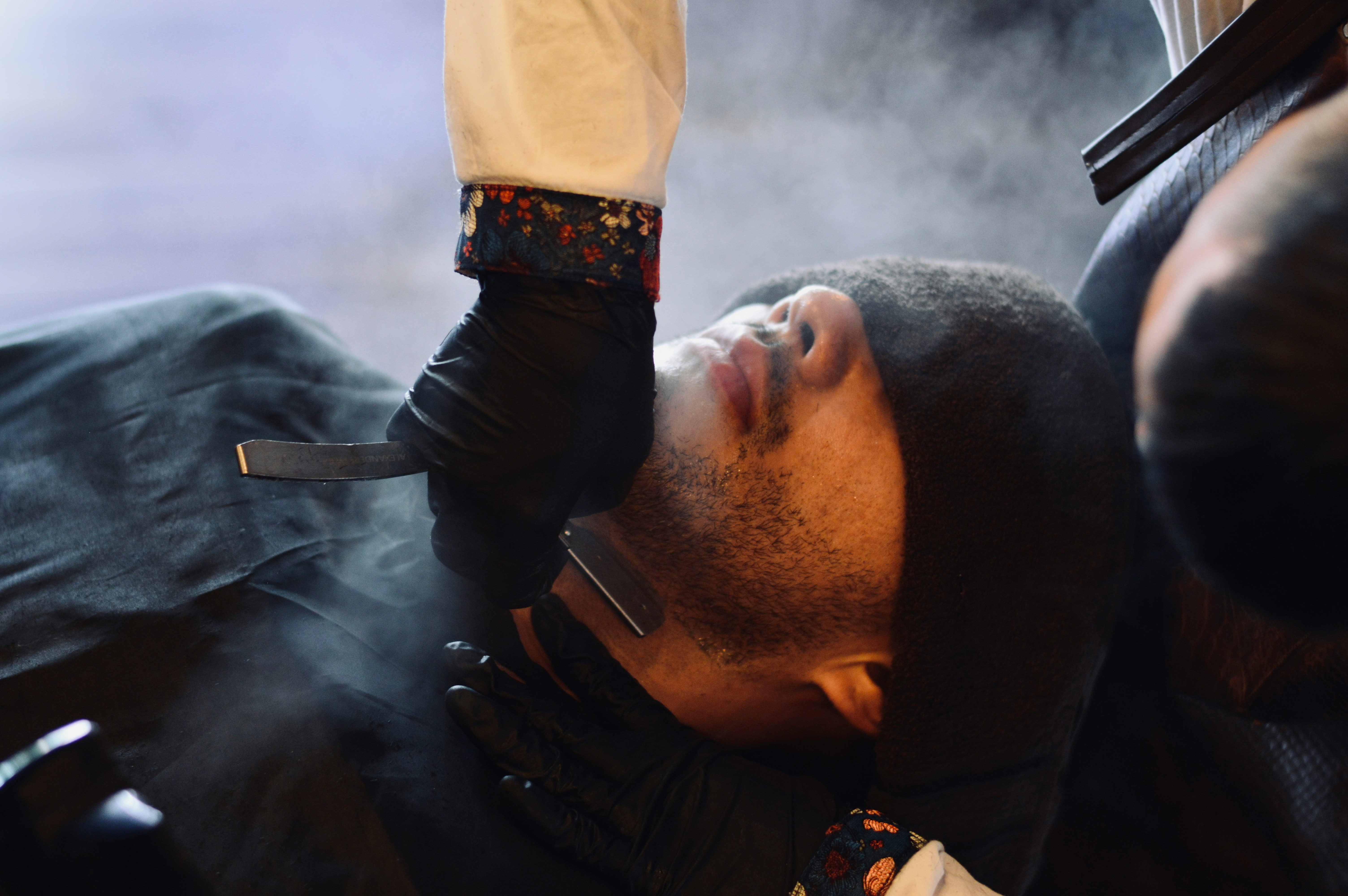 Barber shaves man's beard with straight razor