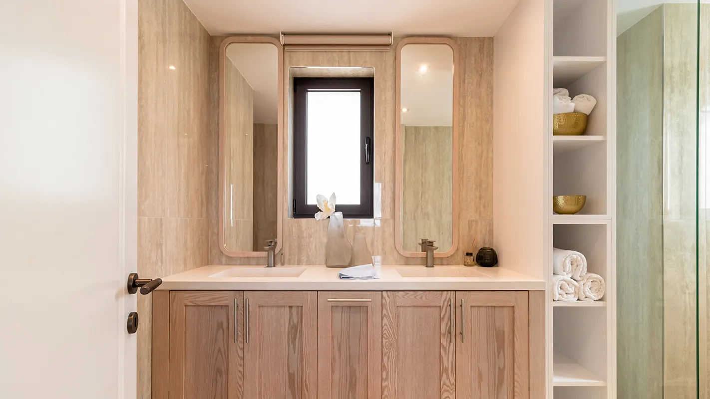 White Cedar House Mediterranean bathroom with wood vanity, double basin, and built-in storage shelving