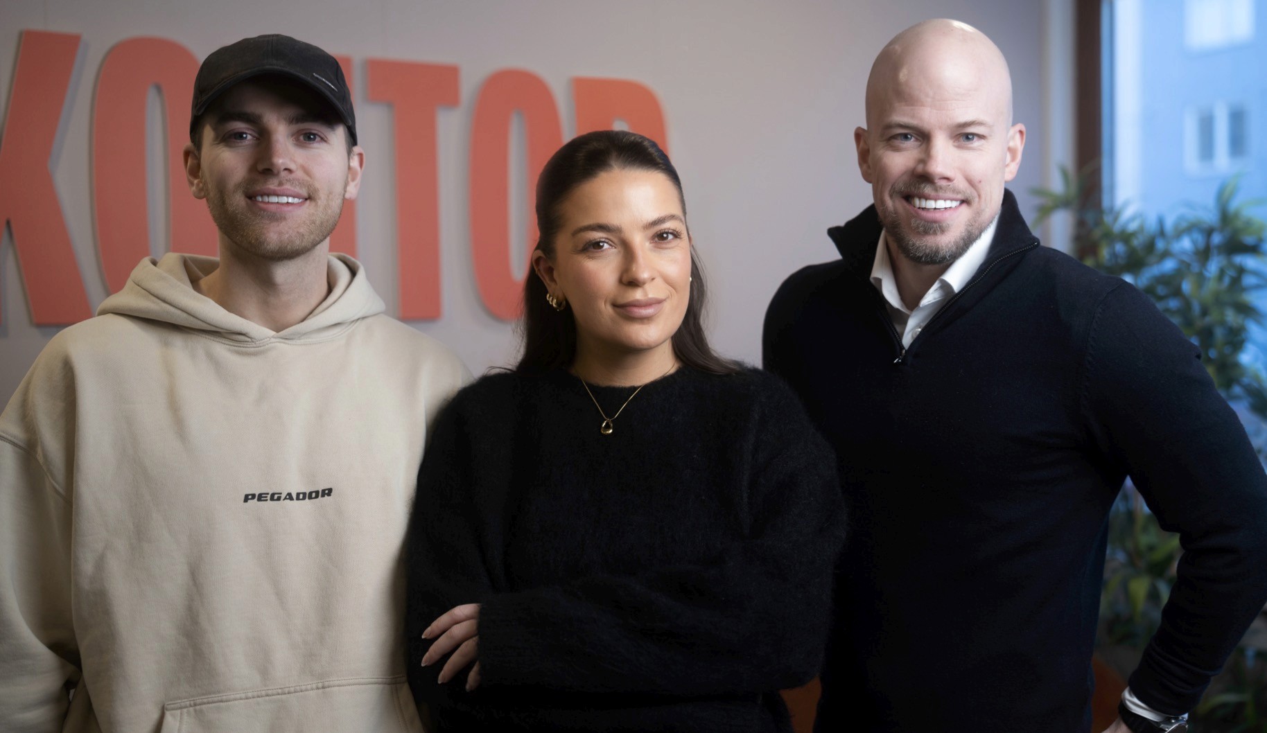 Two people working at desks in a bright, plant-filled office.