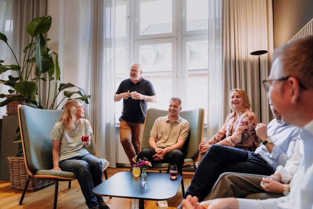 Größere Gruppe von Mitarbeitenden und Geschäftsführern sitzt in einem Stuhlkreis in einem Besprechungsraum von SLB.