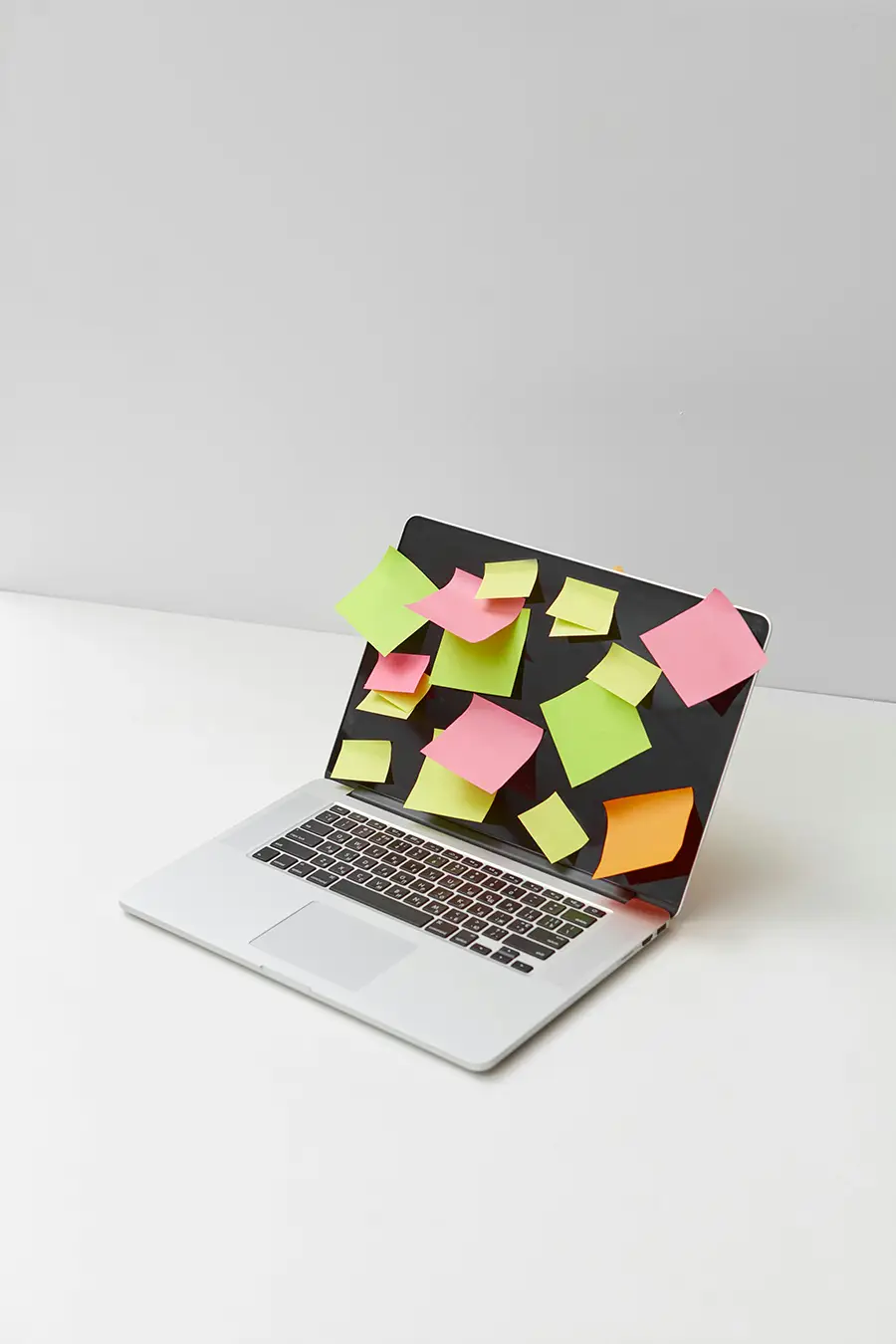 Open laptop with stickynotes in different colours stuck to the screen of it.