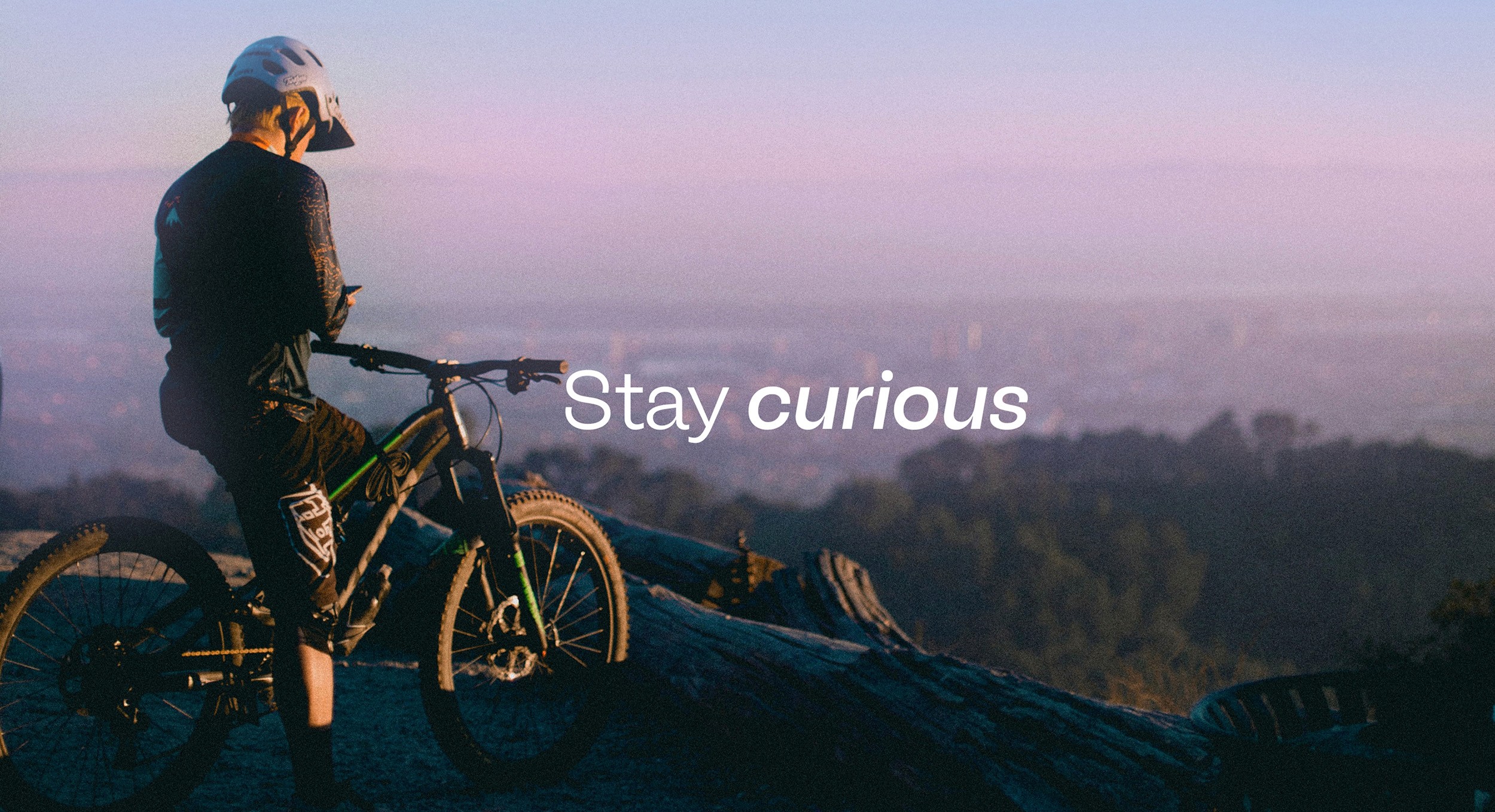 Cyclist standing beside a mountain bike at sunset with campaign messaging overlay, captured as part of the wider Uprise advertising campaign