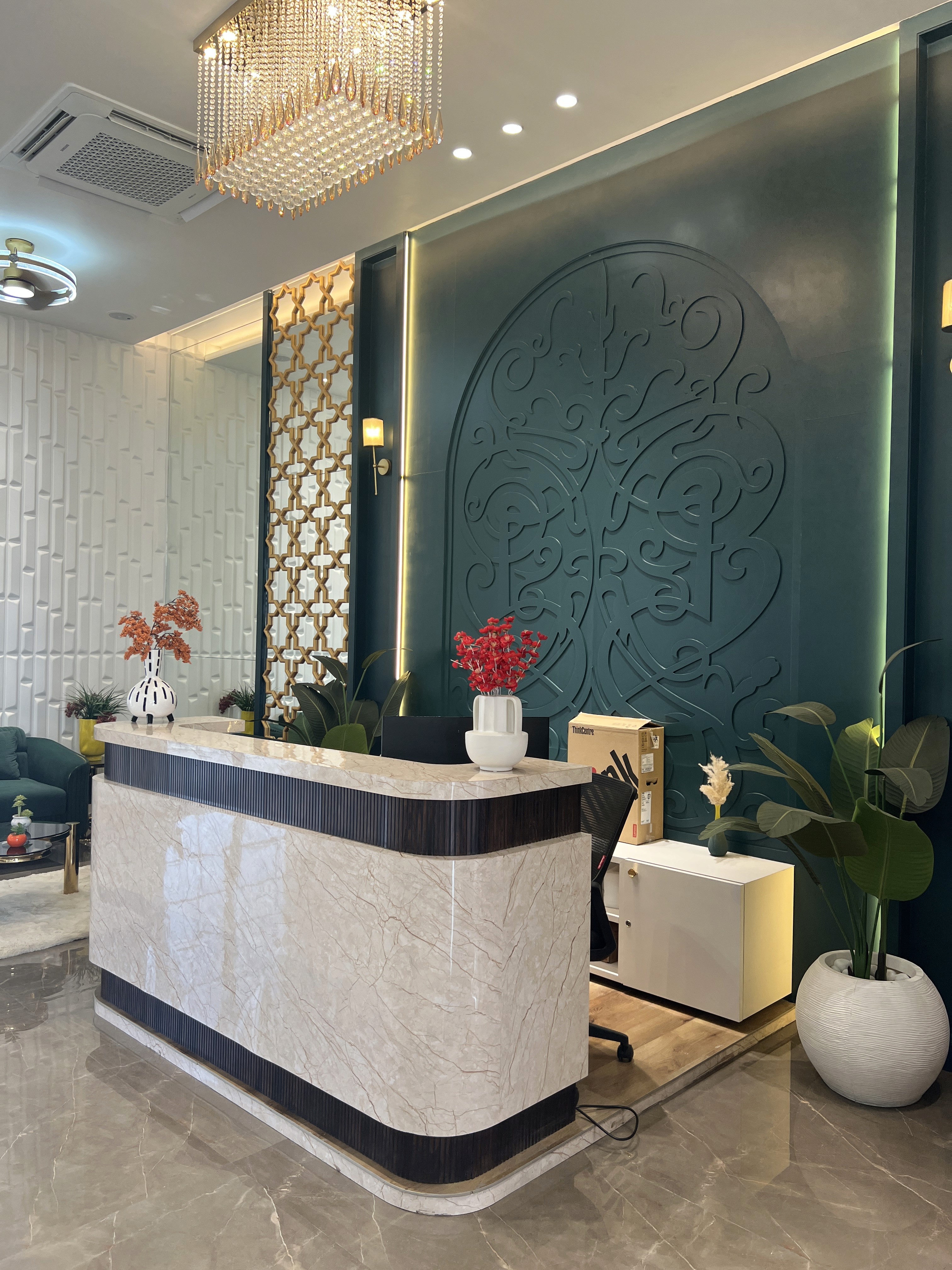 Sophisticated commercial reception desk made of glossy marble with dark wood trim, set against a dark green accent wall with intricate carved patterns.