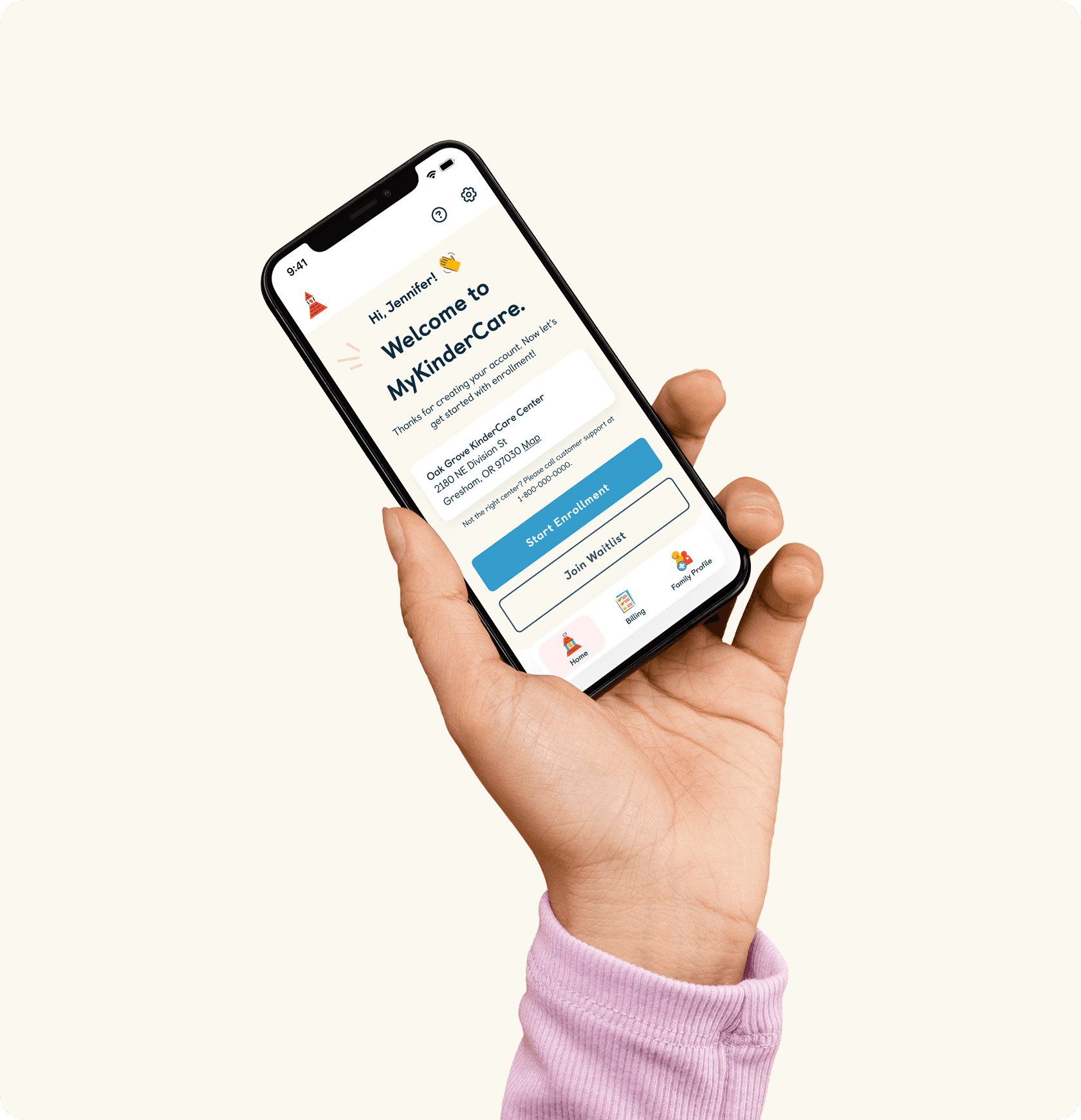 Hand holding smartphone displaying KinderCare parent app welcome screen with parent profile and communication features against warm beige background