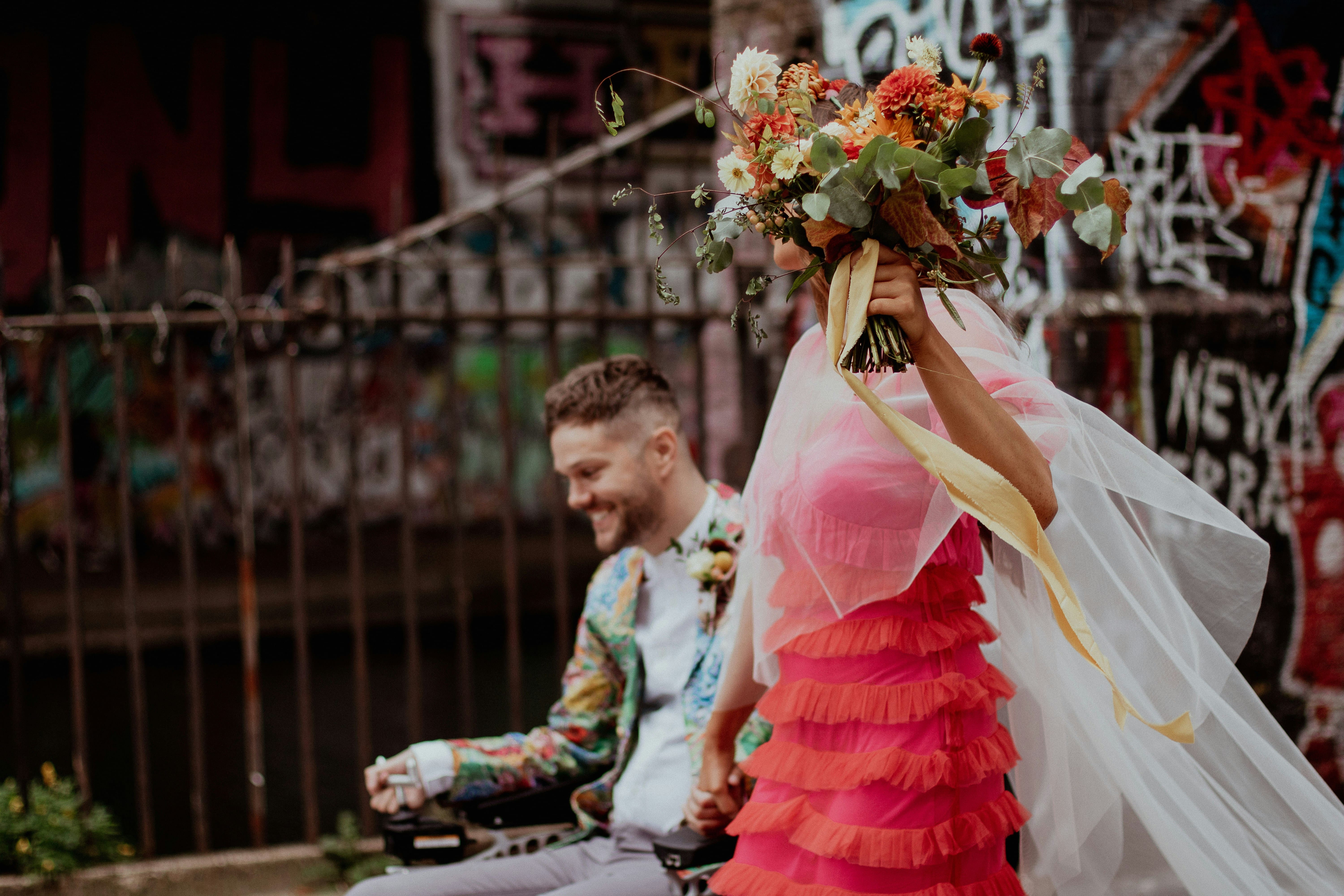 bride and groom non traditional wedding outfits on street with flowers