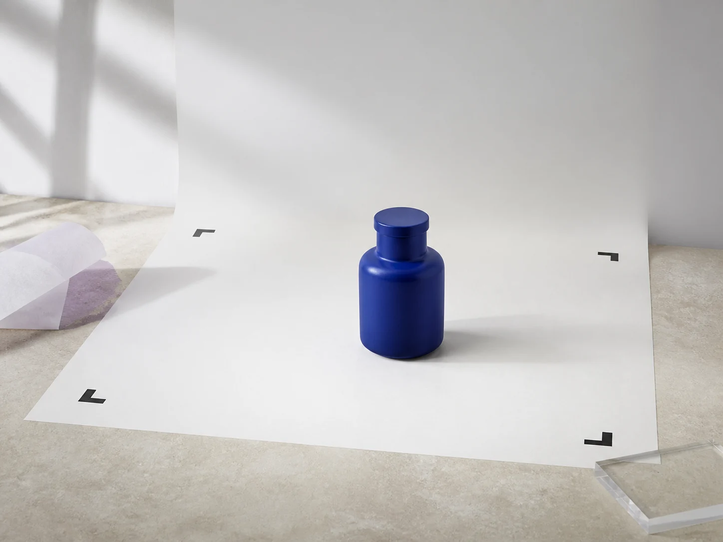 Blue ceramic bottle centered inside four black crop-safe corner marks on a white sweep