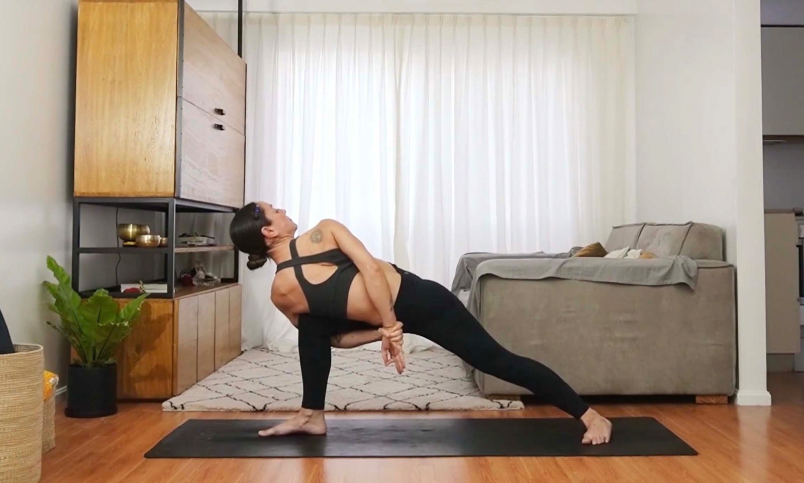 Flavia Siutti realizando una postura de yoga en torsión con una pierna extendida.
