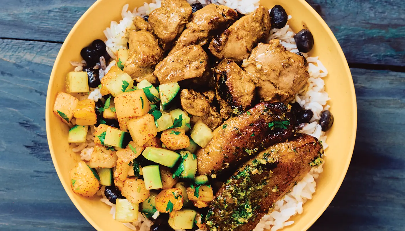 Close-up photograph of a jerk chicken bowl with rice and plantains.