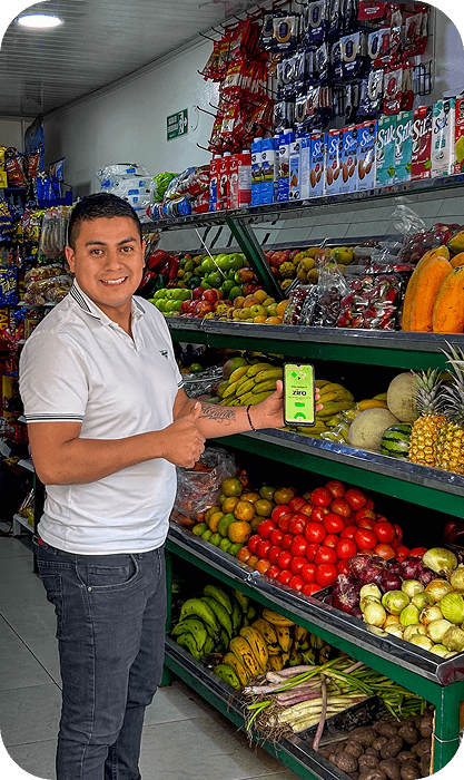 Tendero en su negocio de frutas y verduras mostrando la app de zíro para compras sin intereses