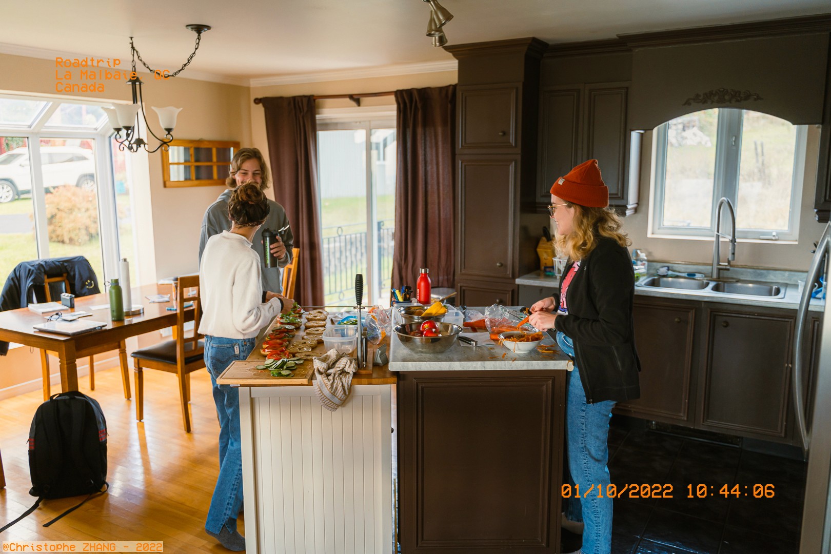 Trois amis préparant un repas ensemble dans une cuisine ensoleillée à La Malbaie.