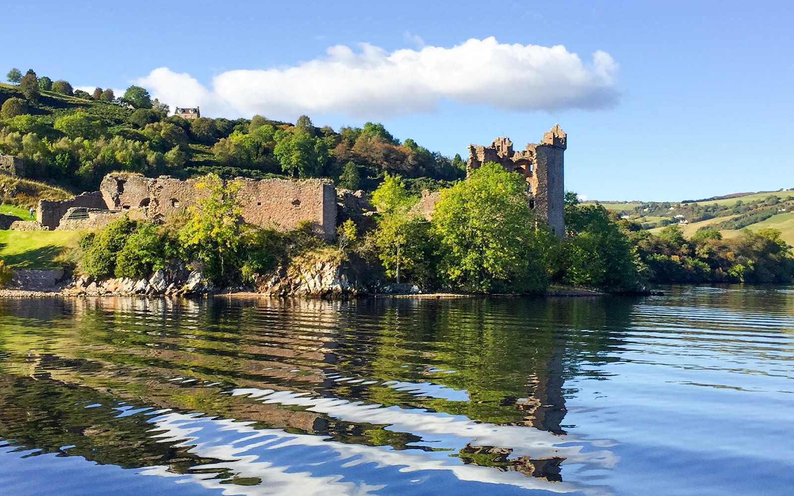 วิวปราสาท Urquhart จากทะเลสาบล็อคเนสส์ สกอตแลนด์ พร้อมด้วยภูเขา Highland โดยรอบ