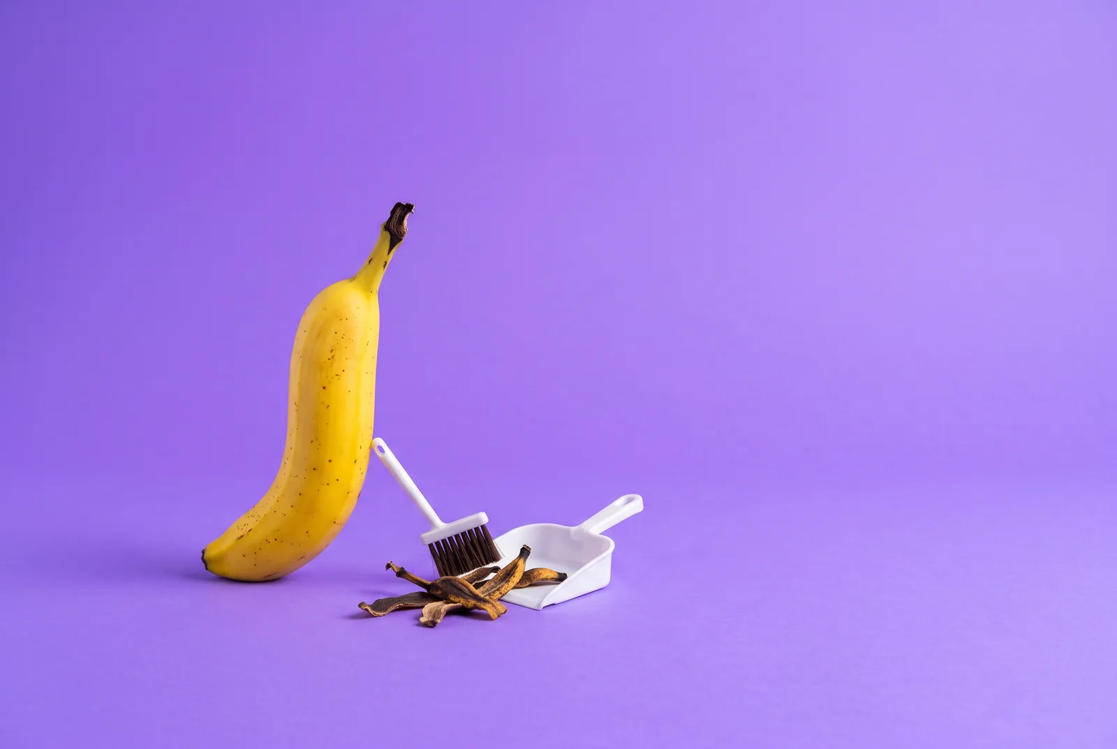 A banana beside a dustpan sweeping up old peels, cleaning up before choosing a Remojo alternative