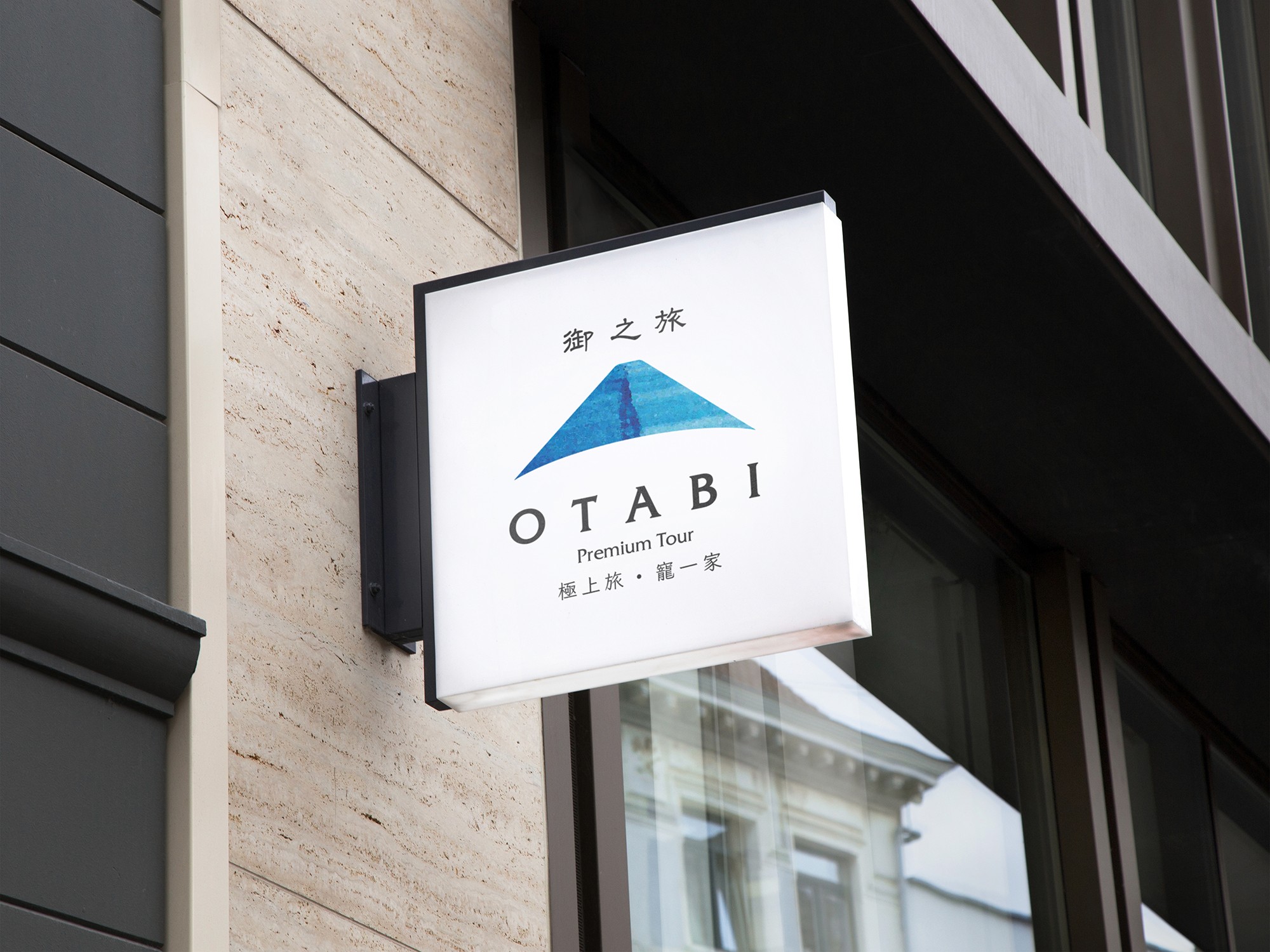 這張圖像展示了另外一款御之旅的品牌標識招牌,識別有一個象徵富士山的標誌,內有漸層的藍色筆刷感,標誌底下寫有「OTABI Premium Tour」和「御之旅」的字。