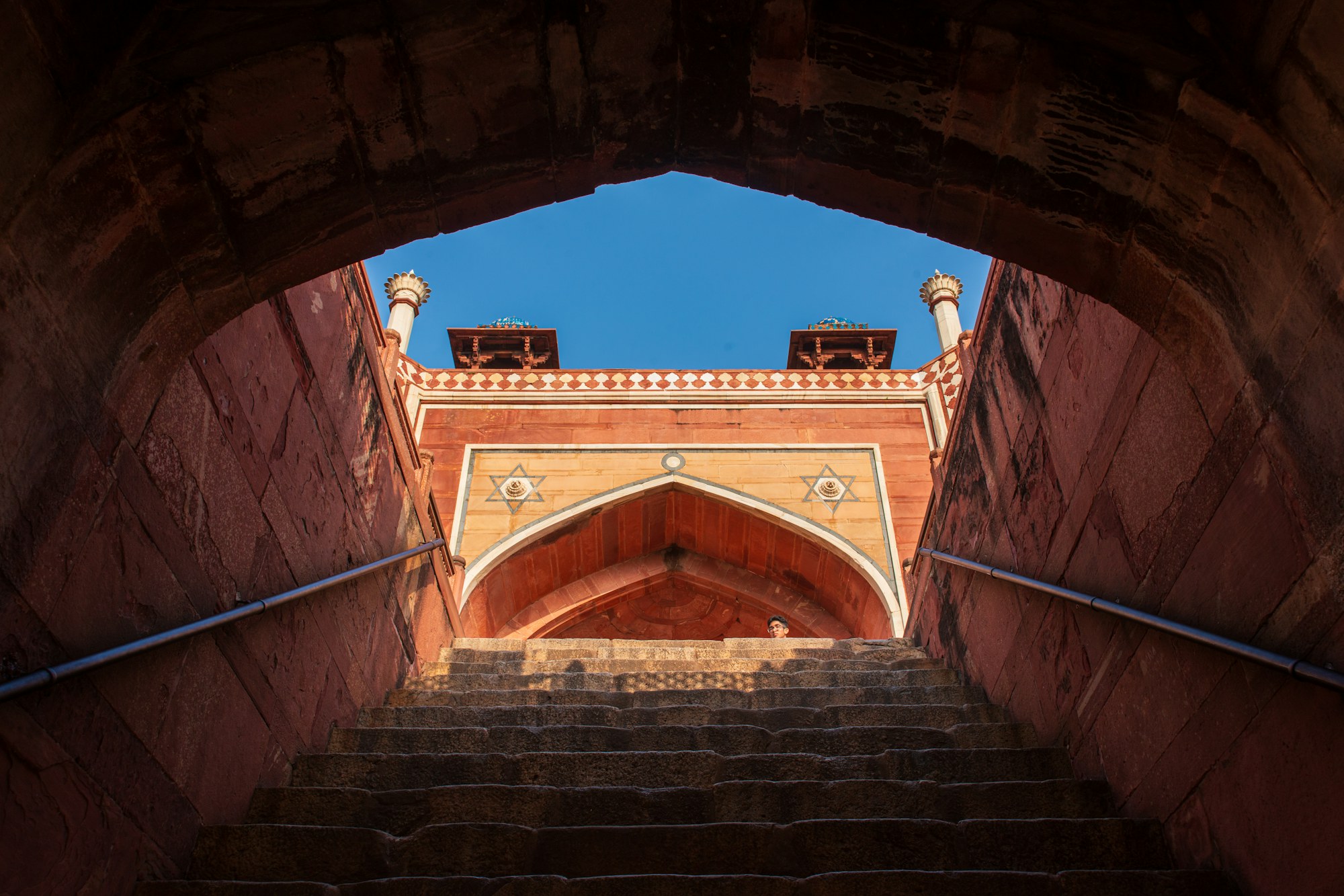 Red sandstone staircase rising towards an arch