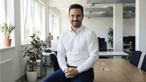 Man in white shirt sitting on table in a bright office, ready for compliance training.
