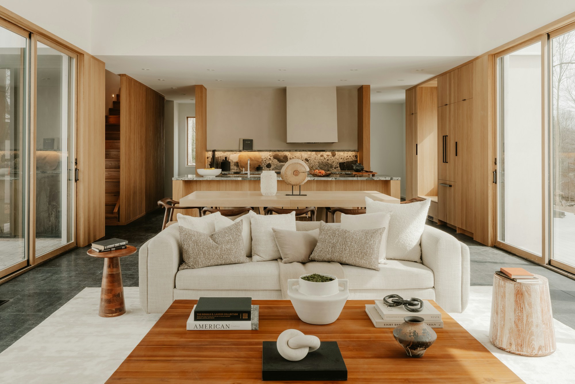 Warm, light-filled living room with a linen sofa, oak coffee table and floor-to-ceiling glass doors