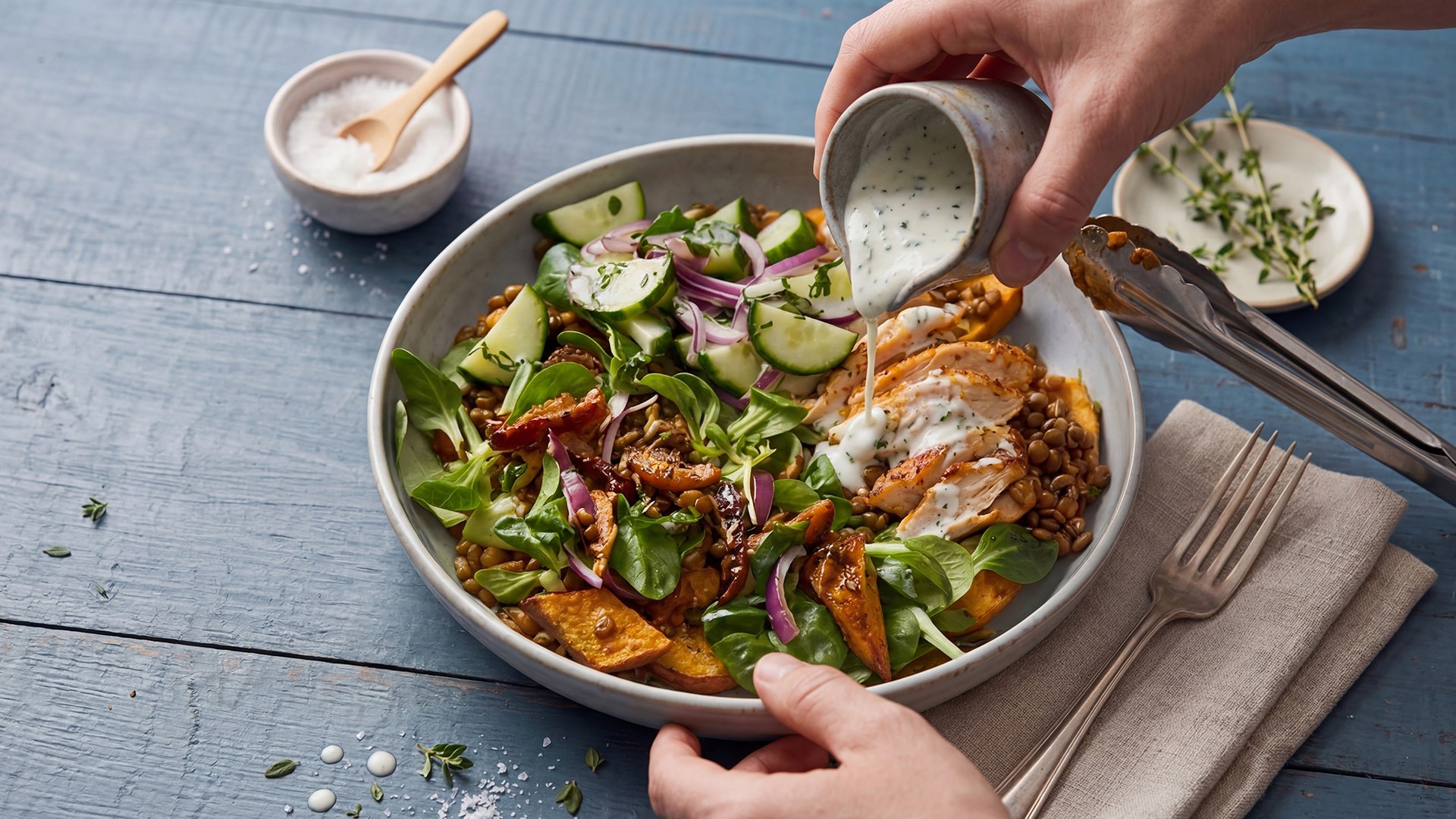 Linsensalat mit Hähnchen, frischem Gemüse und Kräutern wird mit cremigem Dressing verfeinert