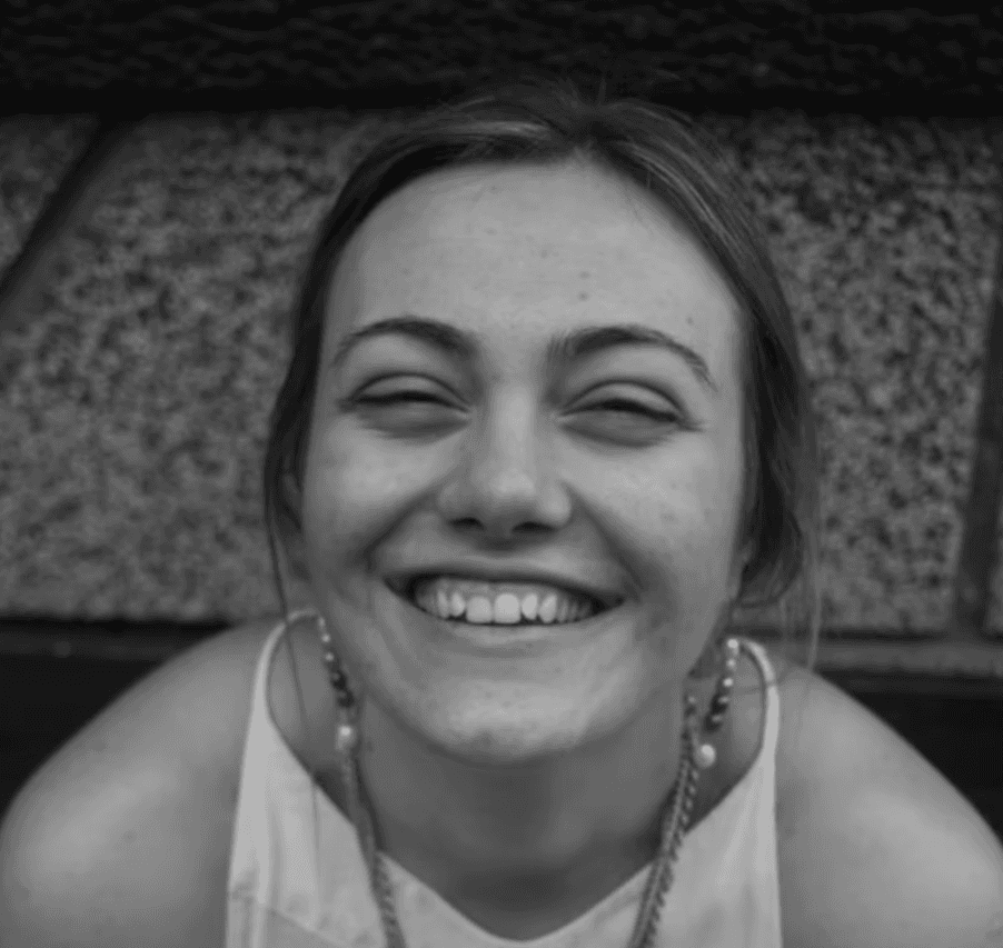 a young man wearing glasses standing in front of a mountain
