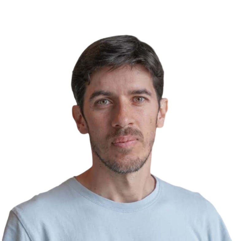 Headshot of a smiling person with tousled blond hair, wearing a black shirt, against a plain white background.