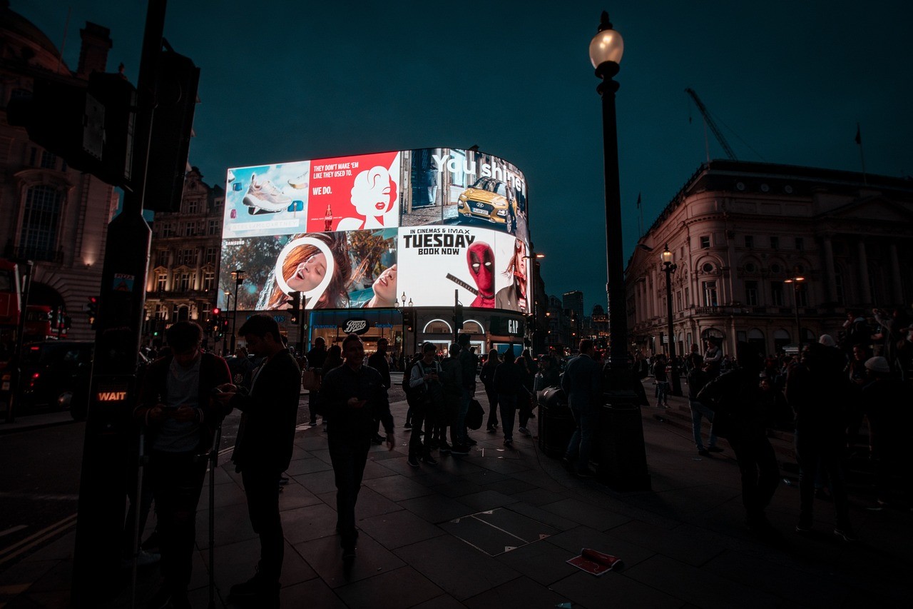 Piccadilly Circus bei Nacht, leuchtende Werbetafeln und Menschenmengen in London.