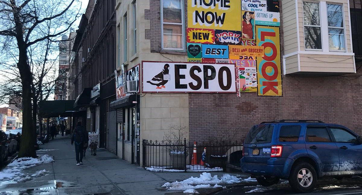 A street view of a building on which there are different artistic banners.