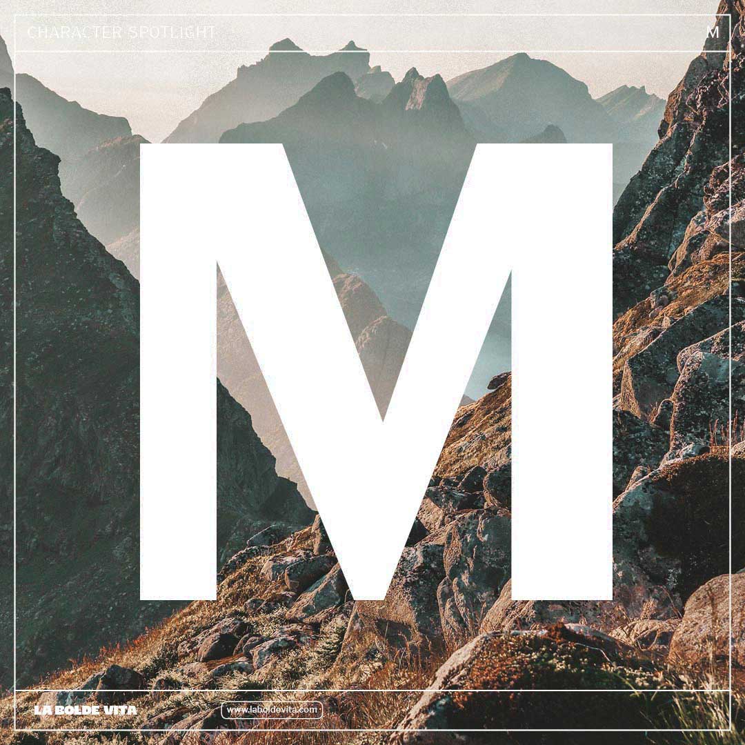 a huge "M" from Kanton Gothic in front of a photo of majestic mountains