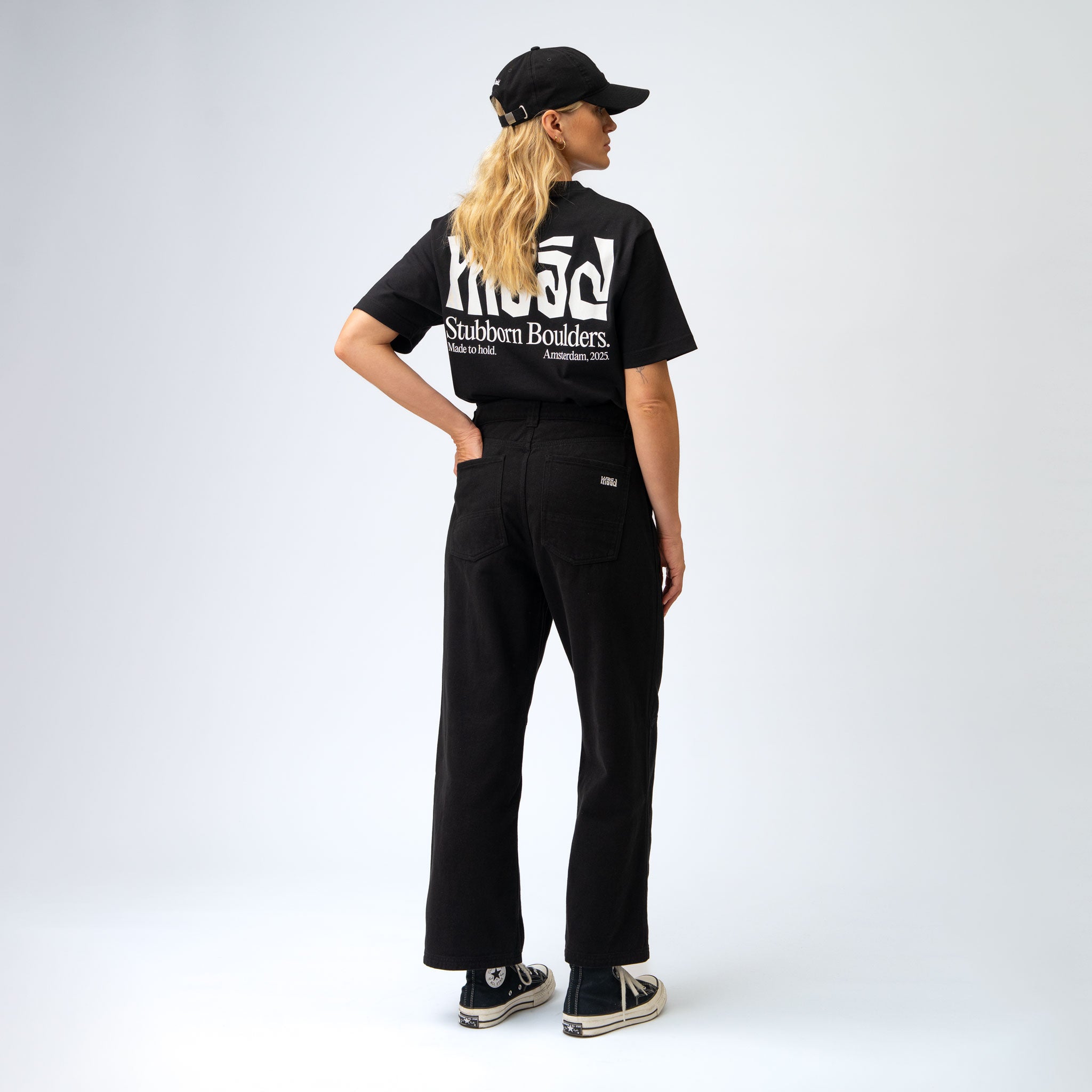 Person wearing a black t-shirt with white text and black pants on a white background