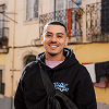 Man in black hoodie smiles outdoors