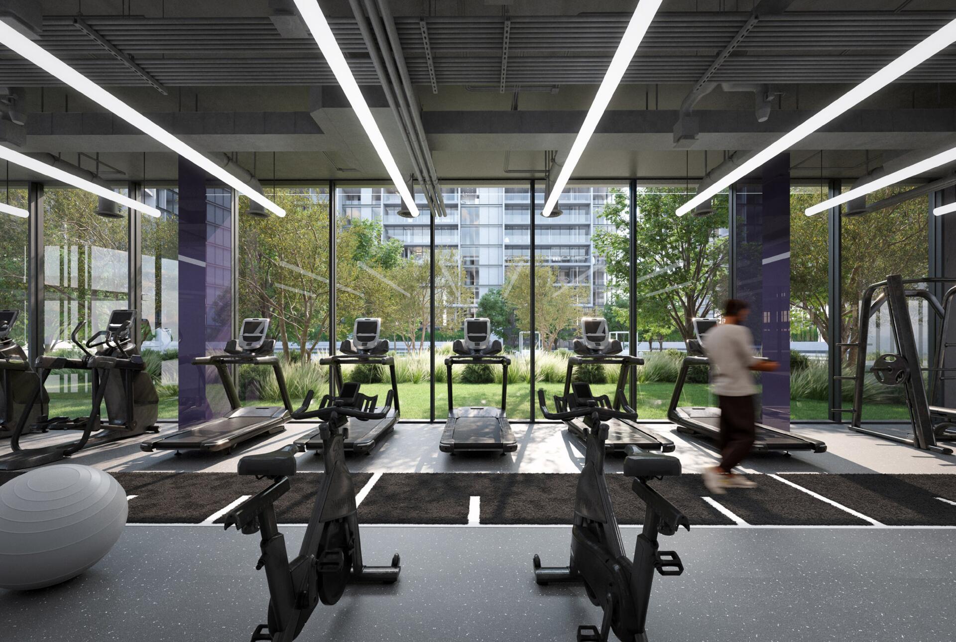 A gym room at The Gate 5 featuring various exercise equipment and people engaged in workouts.