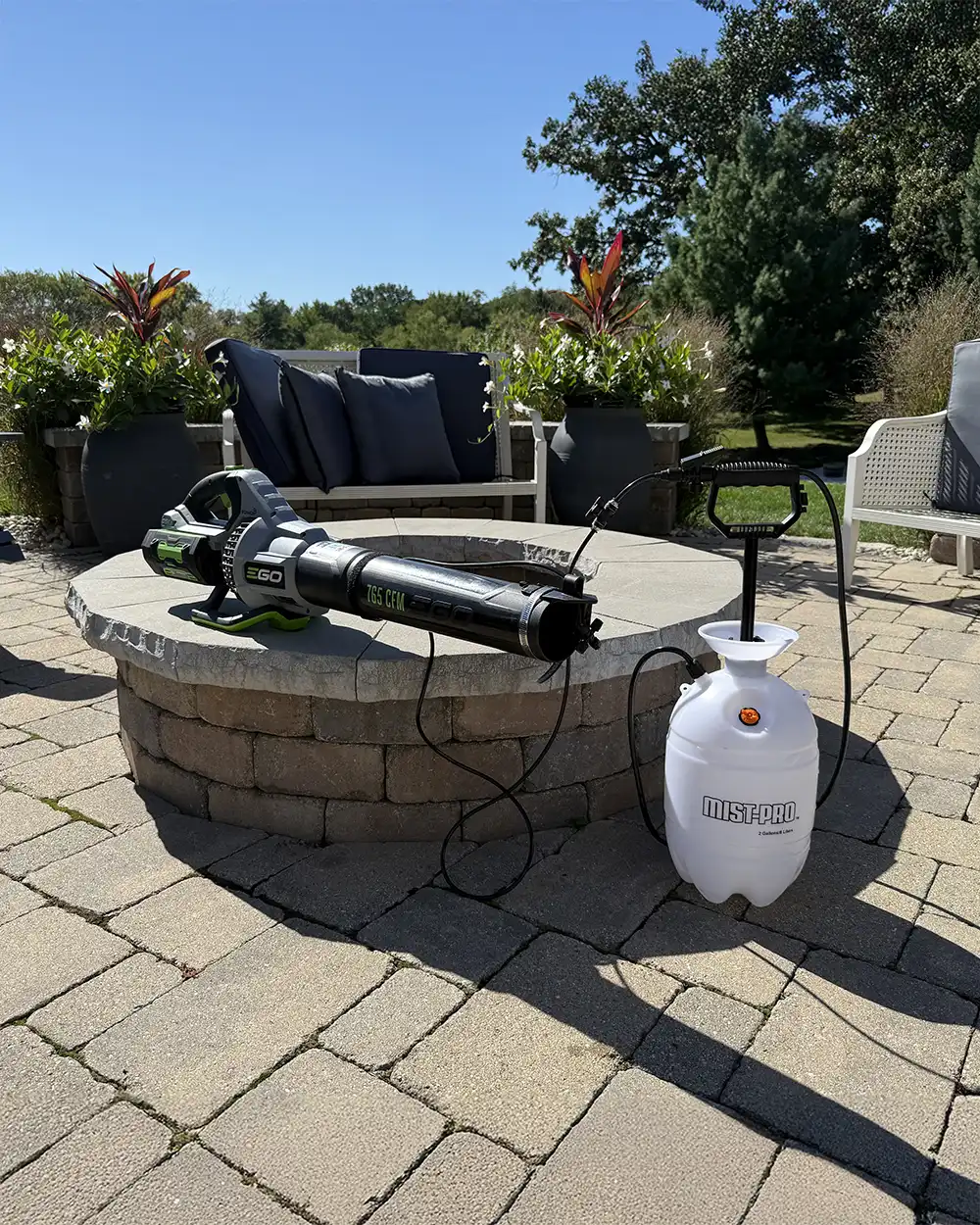 Mist-pro on A stone patio features a large cannon-style sculpture beside a white decorative orb under a clear blue sky.