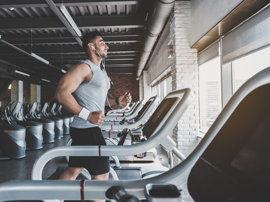 fit man listening to music while he does a longer treadmill weight loss session at the gym