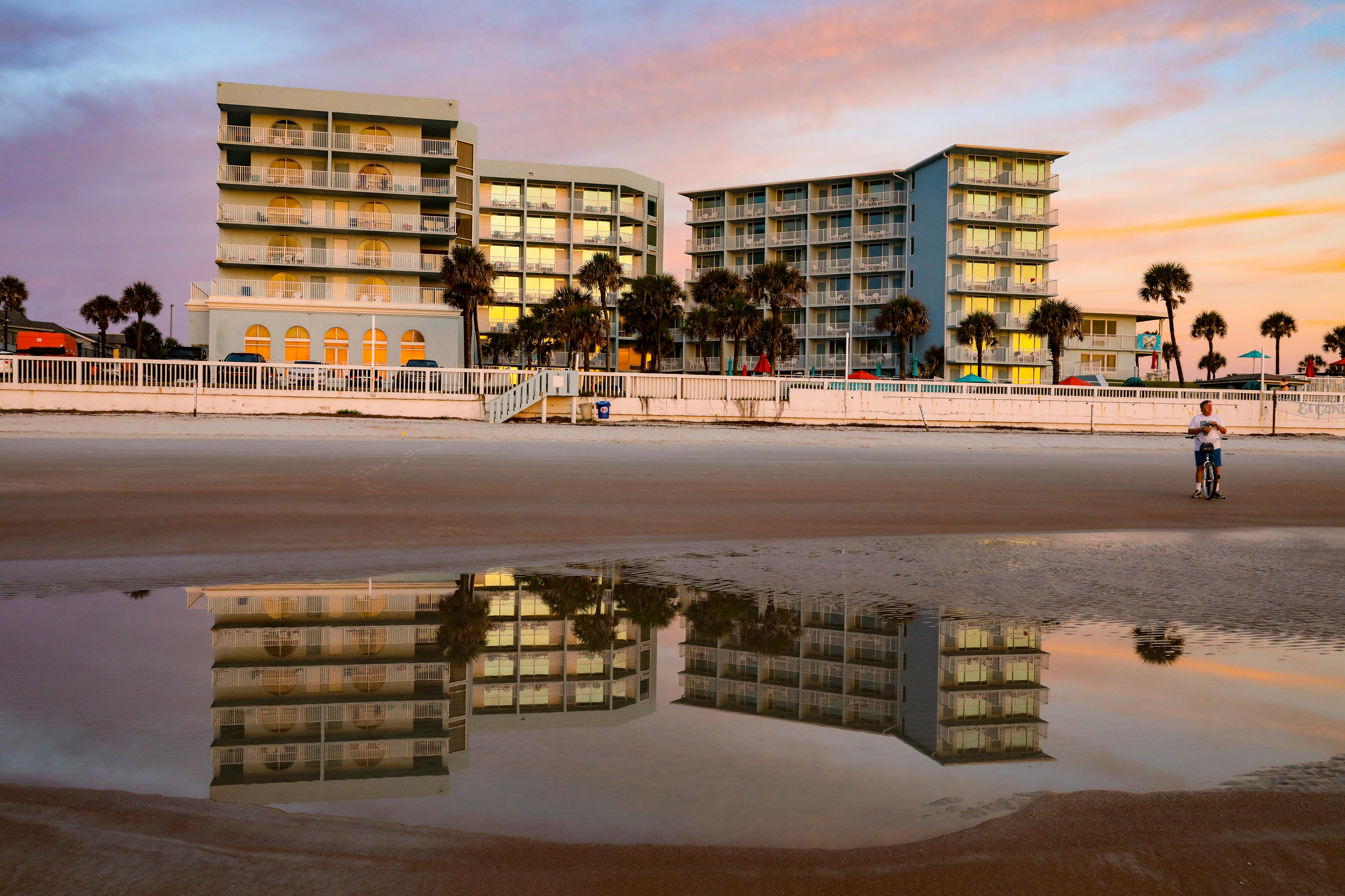 a person walking on a beach near a hotel